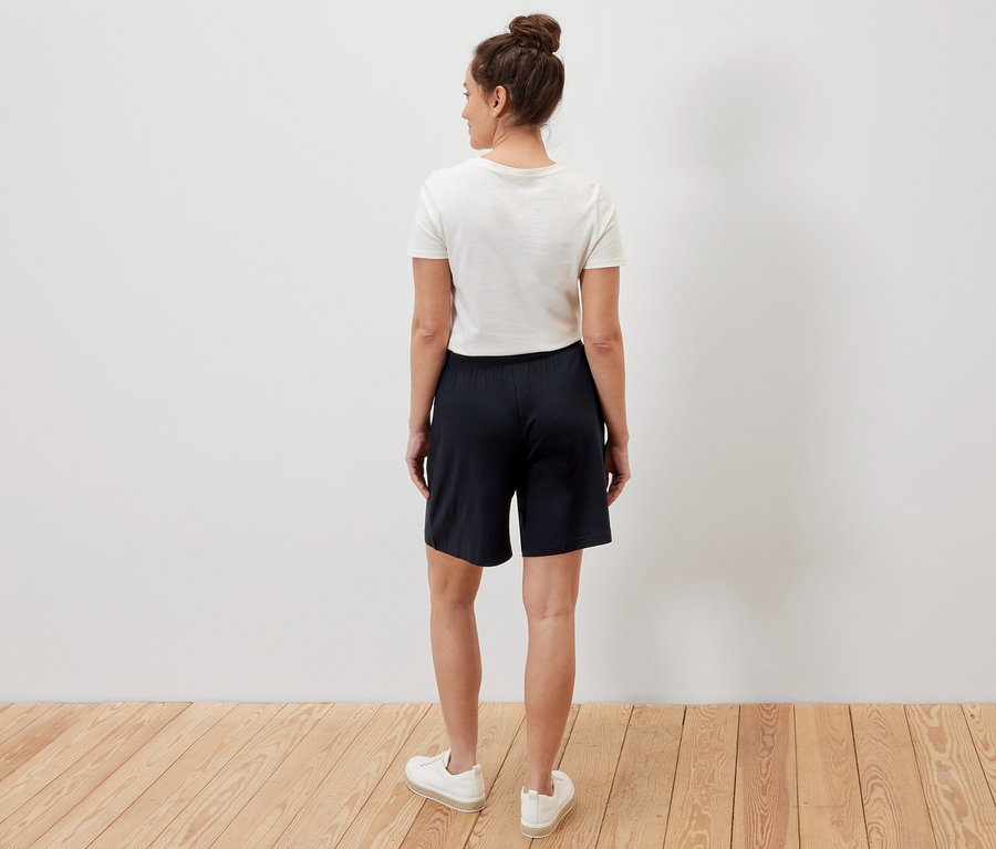 Eine Frau steht mit dem Rücken zur Kamera und trägt schwarze Jerseyshorts.