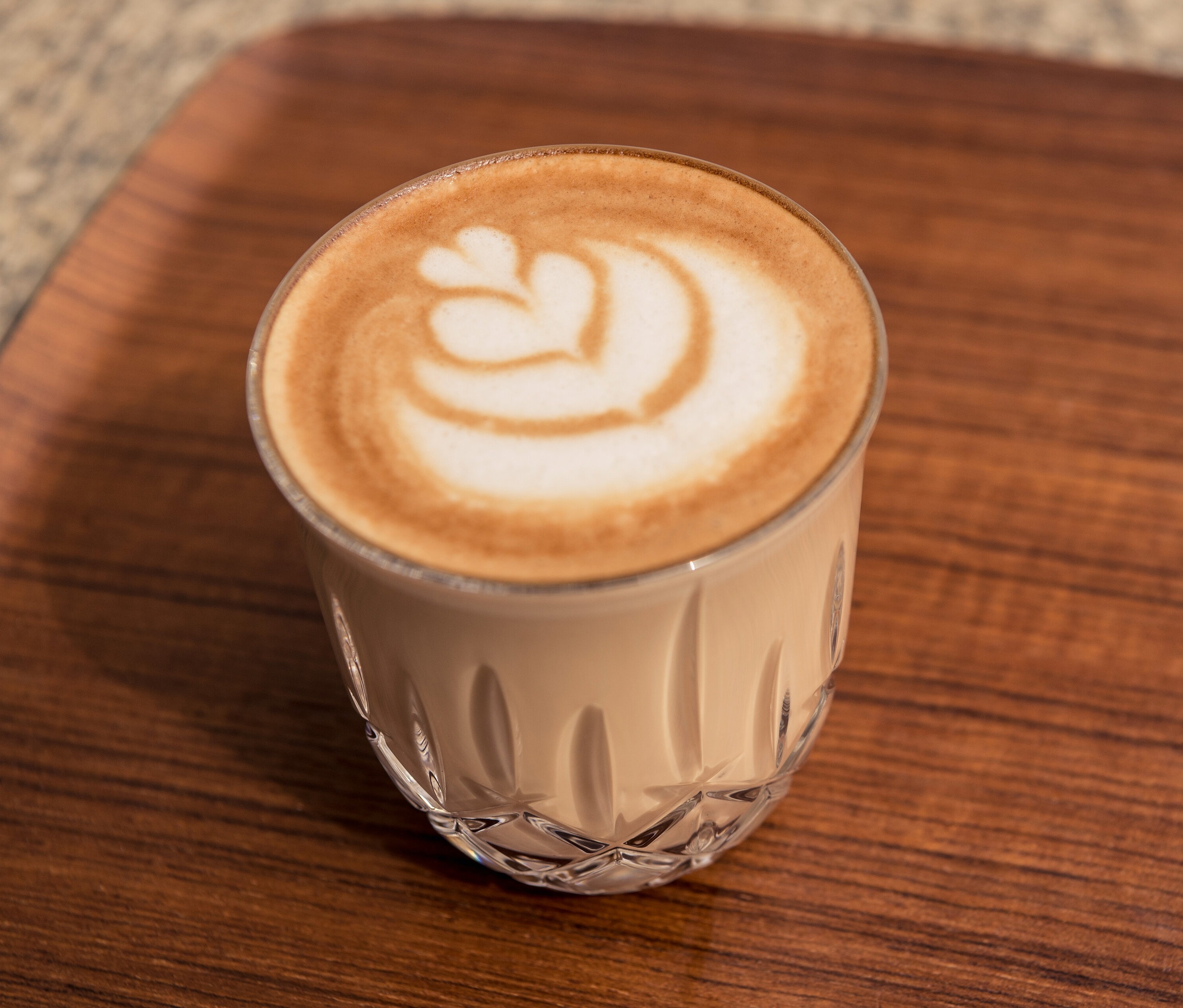 Ein Cappuccino mit Herzmuster im 6 Nachtmann Cappuccinogläser »Noblesse« auf einem Holztisch.