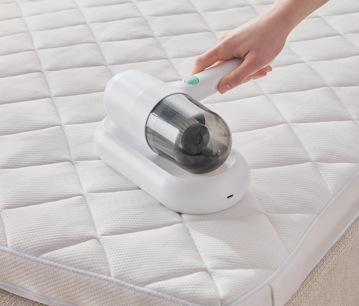 Eine Hand verwendet einen Milbensauger auf einer weißen Matratze.