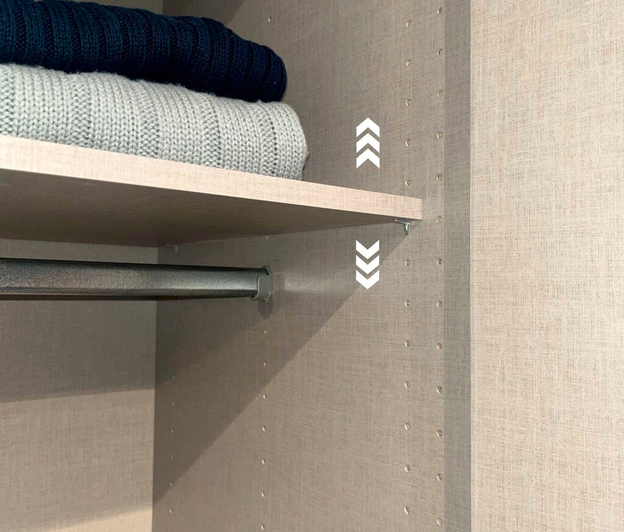 Im Kleiderschrank liegen ein grauer und ein marineblauer Pullover auf einem Regal über einer Kleiderstange.