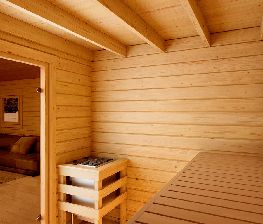Innenraum einer Sauna mit Holzofen und Sitzbank, Holzwände und -decke