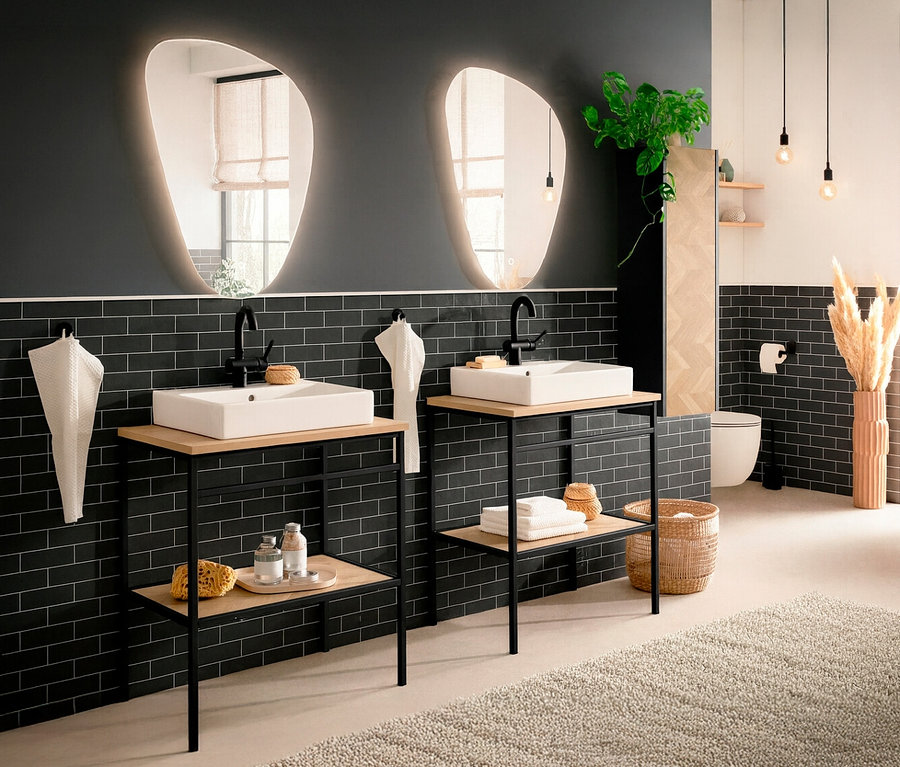 Zwei Waschtische mit schwarzen Armaturen stehen vor einer schwarzen Backsteinwand in einem Badezimmer.