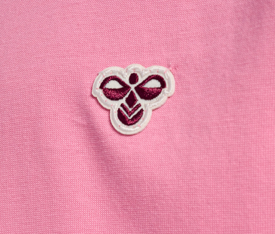 Nahaufnahme eines rosa Stoffes mit einem kleinen, gestickten Logo in der oberen Mitte.