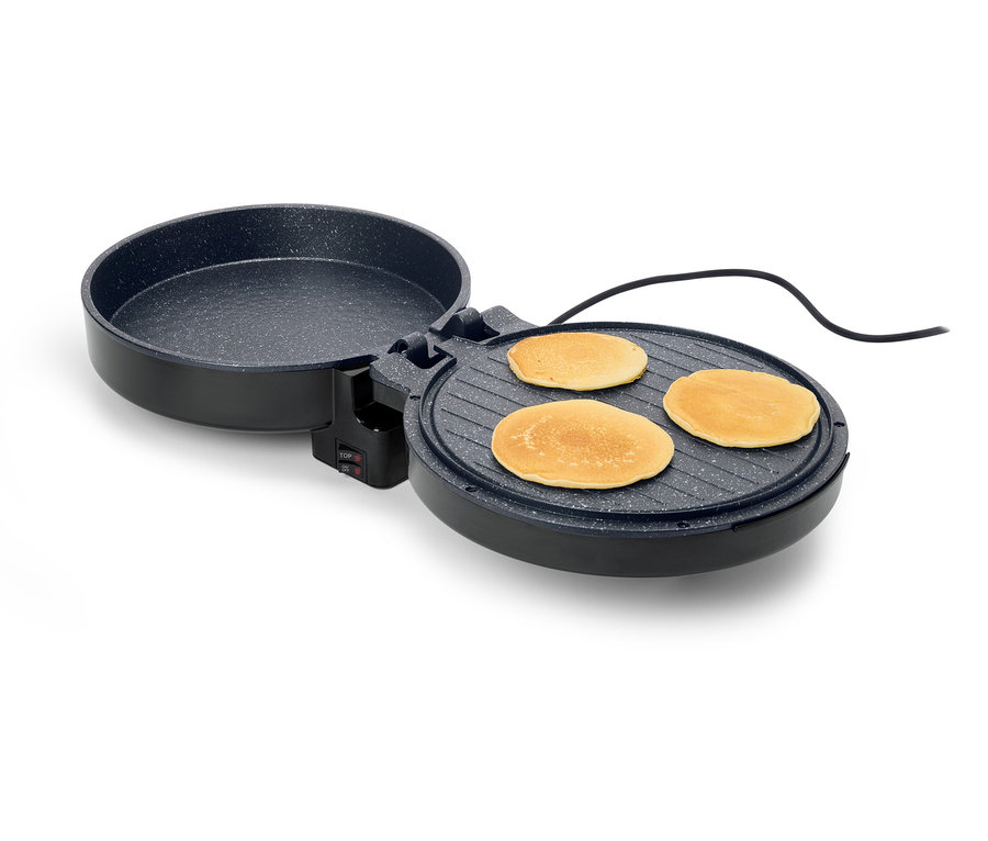 Ein offener, runder, schwarzer Crêpe-Maker mit drei Crêpes darauf, vor einem weißen Hintergrund.