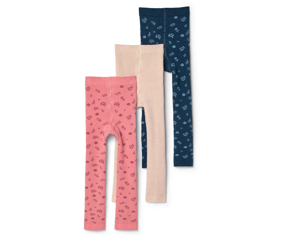 Drei Kinderleggings in Rosa mit Muster, Beige und Dunkelblau mit Muster liegen übereinander.