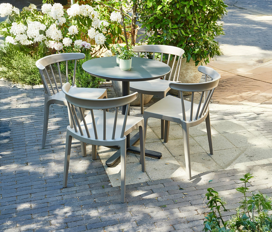 Runder Tisch umgeben von vier salbeigrünen WOOOD Gartenstühlen.