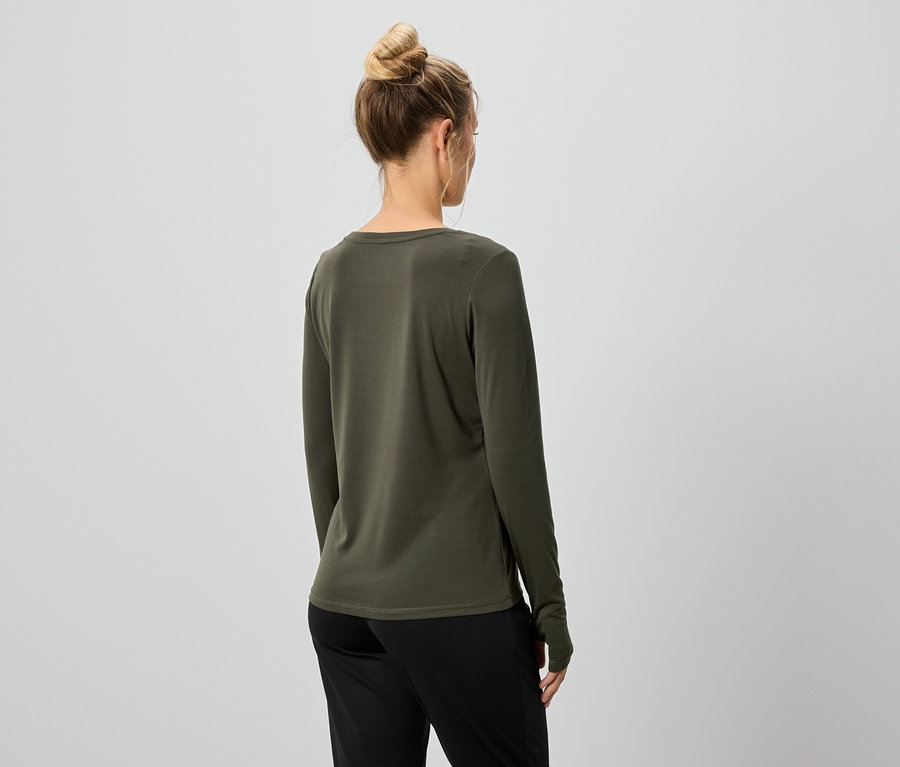 Rückansicht einer Frau mit Dutt, die ein olivgrünes Langarmshirt und eine schwarze Hose trägt.