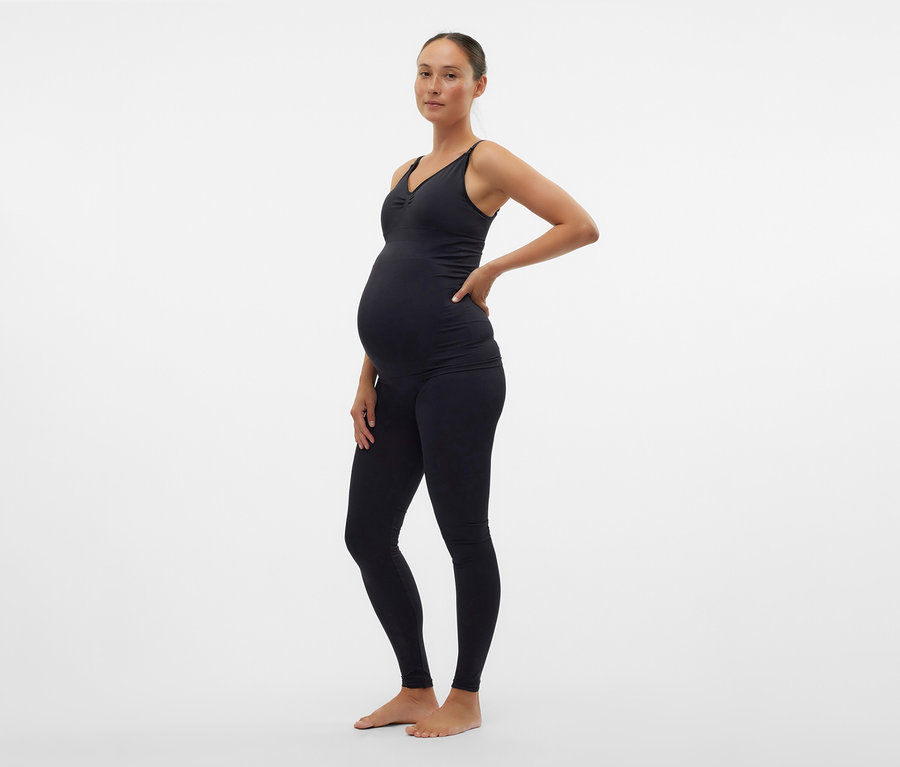 Schwangere Frau in schwarzem Top und MAMALICIOUS Skinny Leggins »MLTIA JEANNE« posiert seitlich.