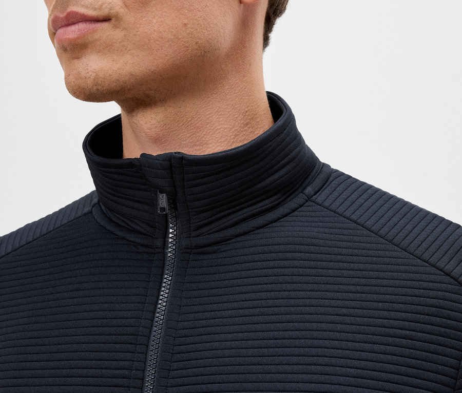 Nahaufnahme eines Mannes, der eine marineblaue Jacke mit Reißverschluss und Stehkragen trägt.