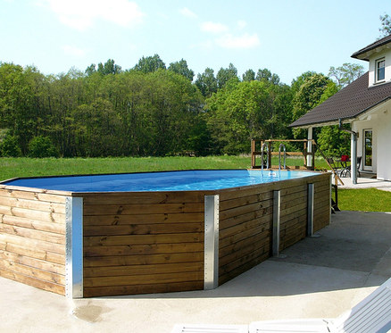 Ein rechteckiger Holzpool mit Metallstützen steht auf einer Terrasse neben einem weißen Haus. Weka-Massivholz-Gartenpool inkl. Abdeckhaube, ca. 714 x 376 x 116 cm
