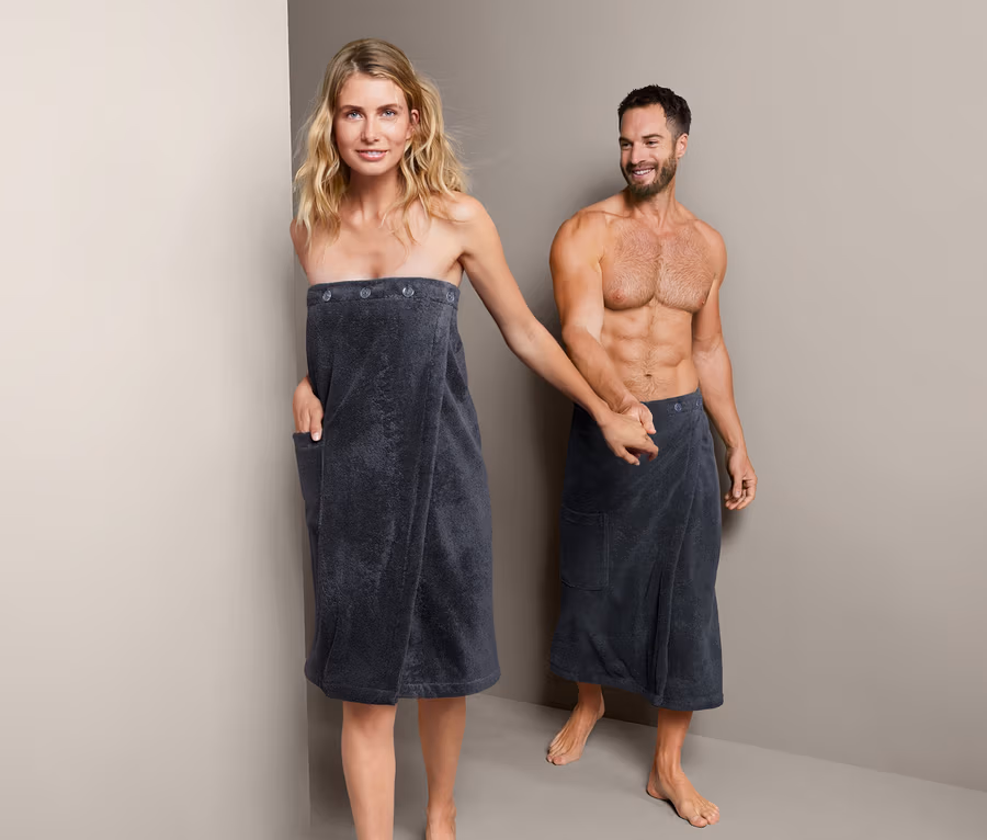 Frau und Mann halten Händchen, beide tragen einen Unisex-Sauna-Kilt.