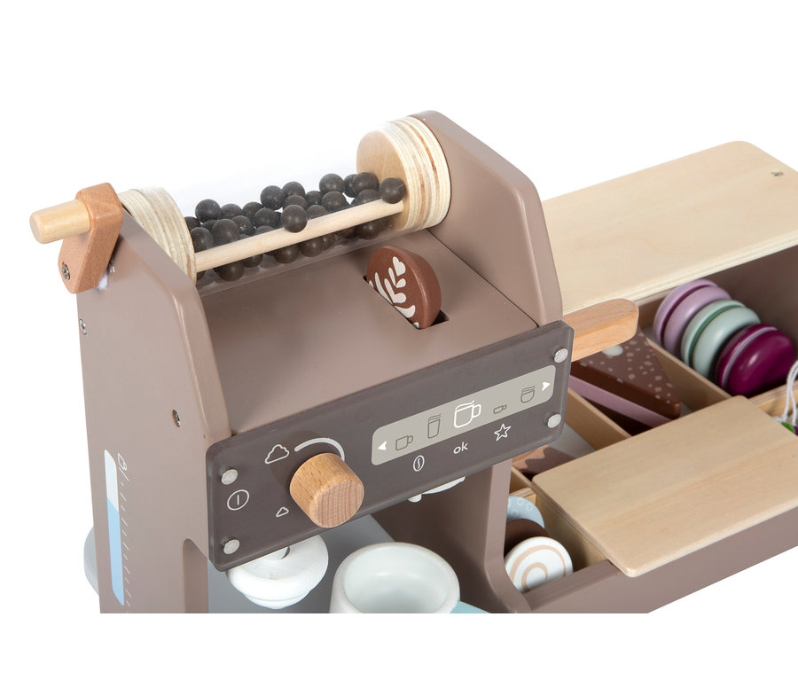 Hölzernes Spielzeug-Kaffeehaus mit Kaffeemaschine, die Kaffeebohnen und Latte Art-Scheiben hat, sowie einer Theke mit bunten Macarons und Kuchenstücken.