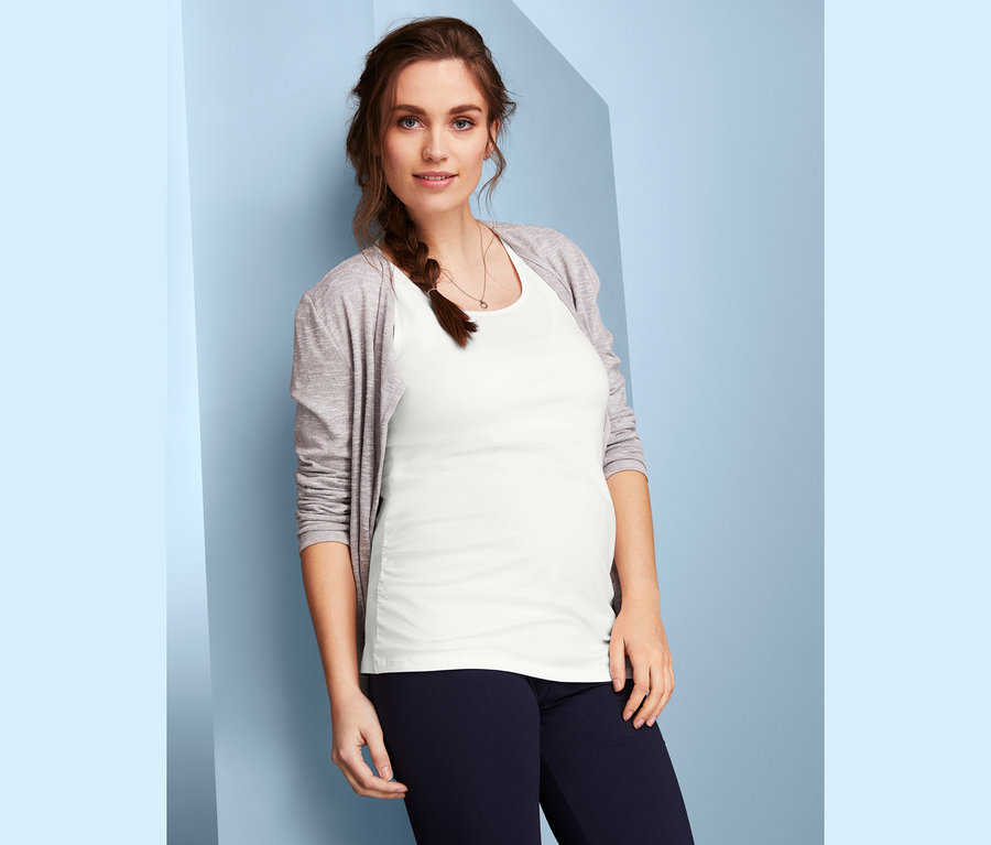 Schwangere posiert in weißem Top aus einem 2er-Pack Umstands-Tops und grauem Cardigan.