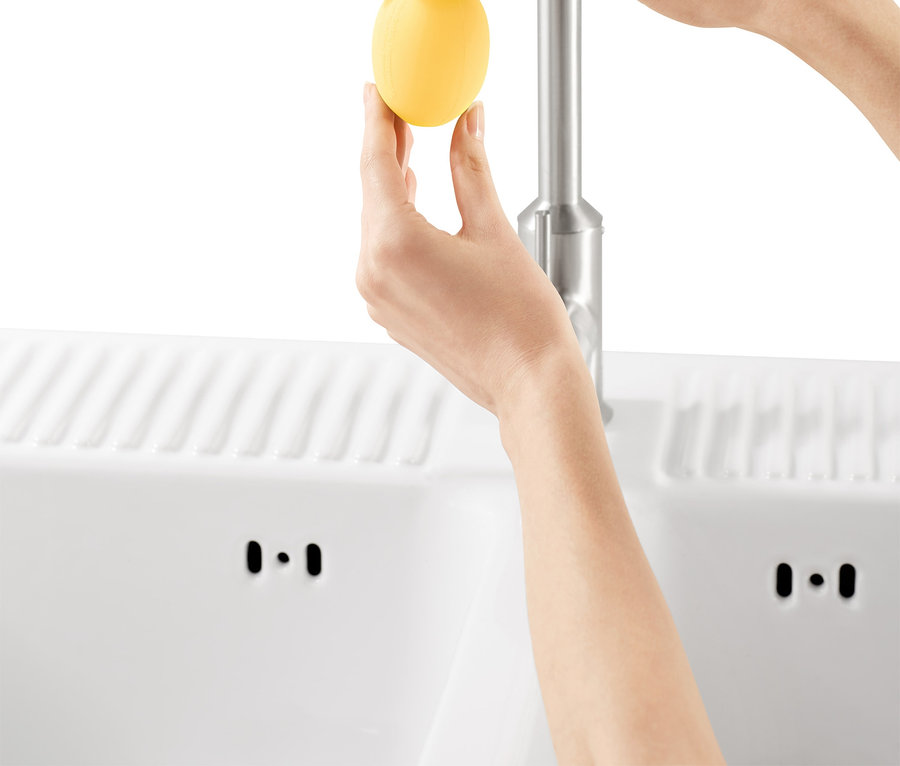 Frau befestigt Wasserhahn-Entkalker-Aufsatz am Wasserhahn.