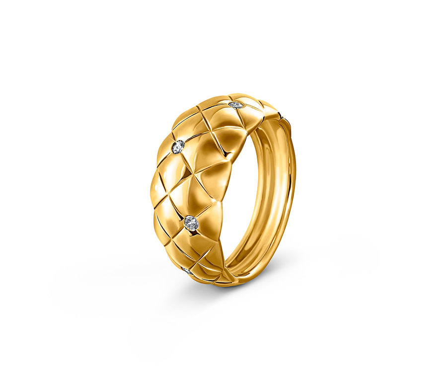Nahaufnahme eines goldenen Rings mit geometrischem Muster und eingesetzten Steinen.