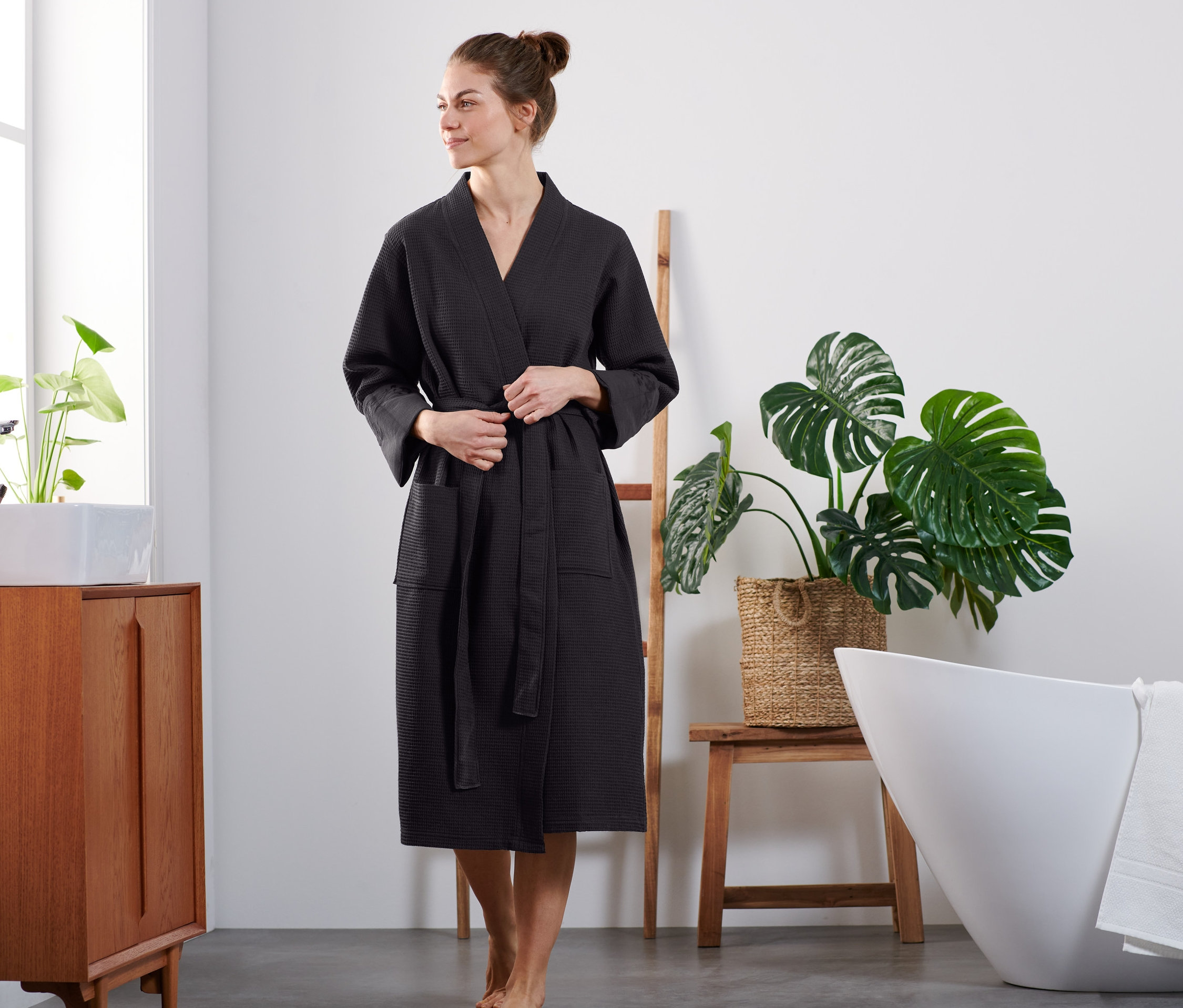 Frau bindet schwarzen Bademantel.