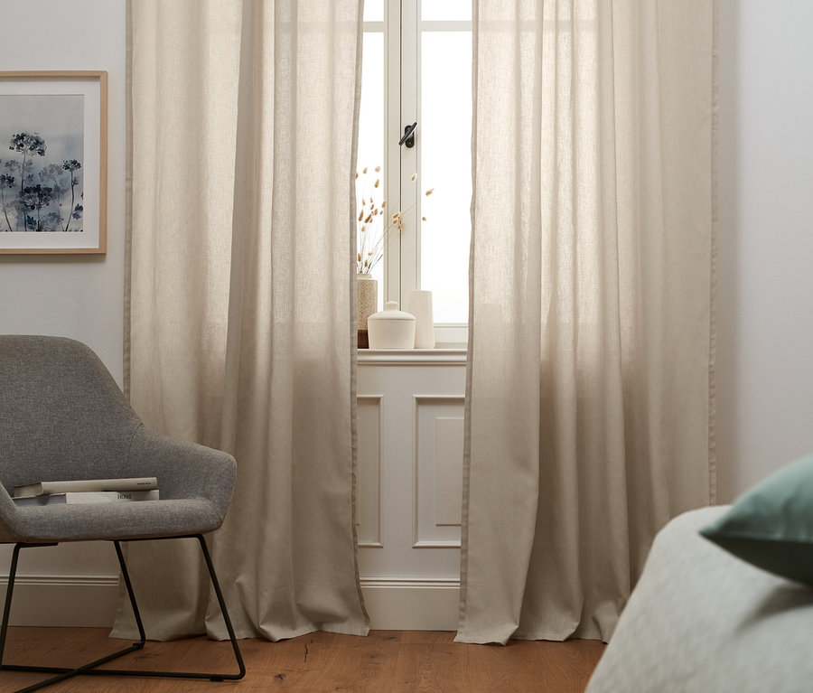 Beige Halbleinen-Vorhangschals verdecken das Fenster.