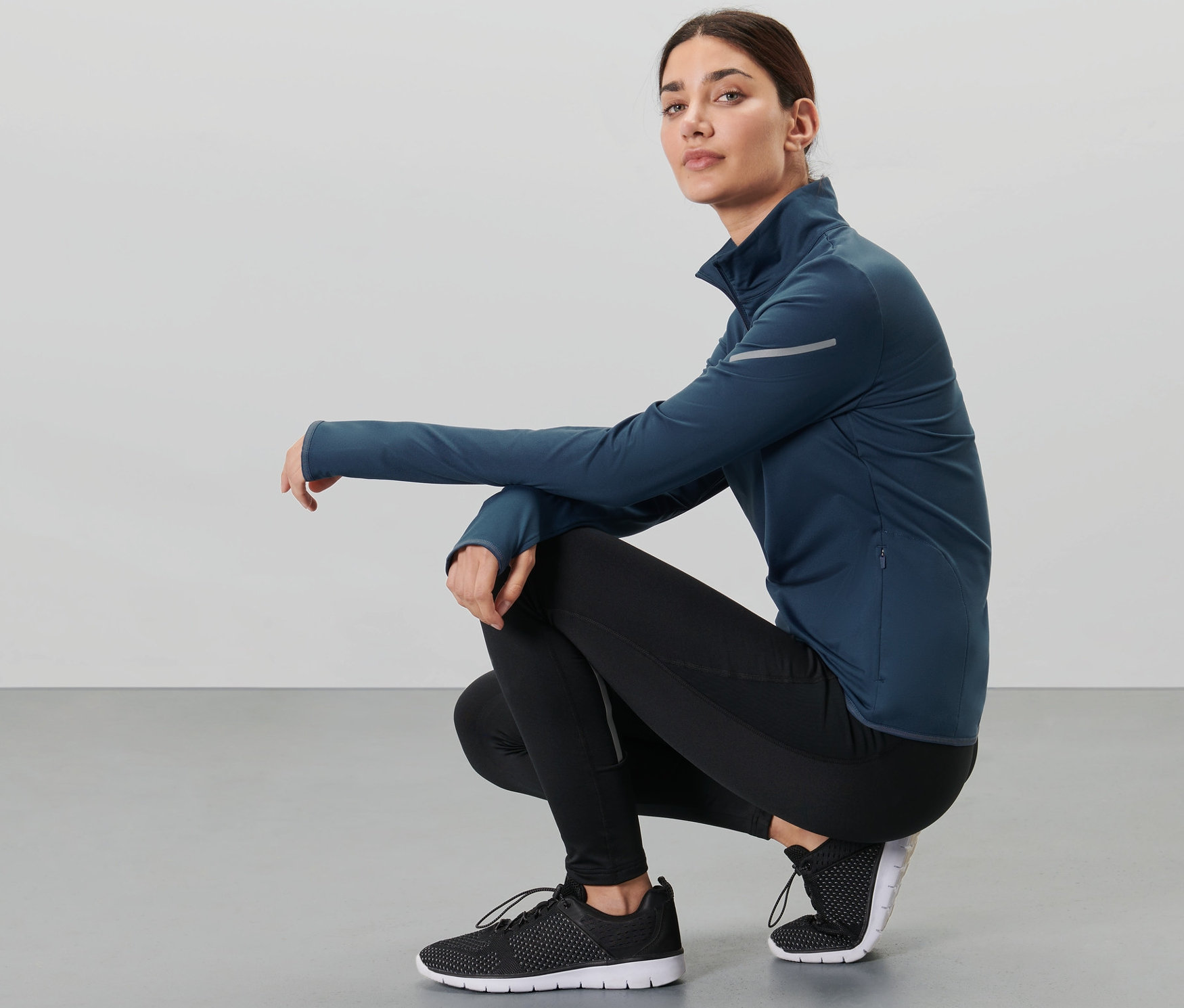 Eine hockende Frau trägt ein dunkelblaues Thermo-Funktionsshirt.
