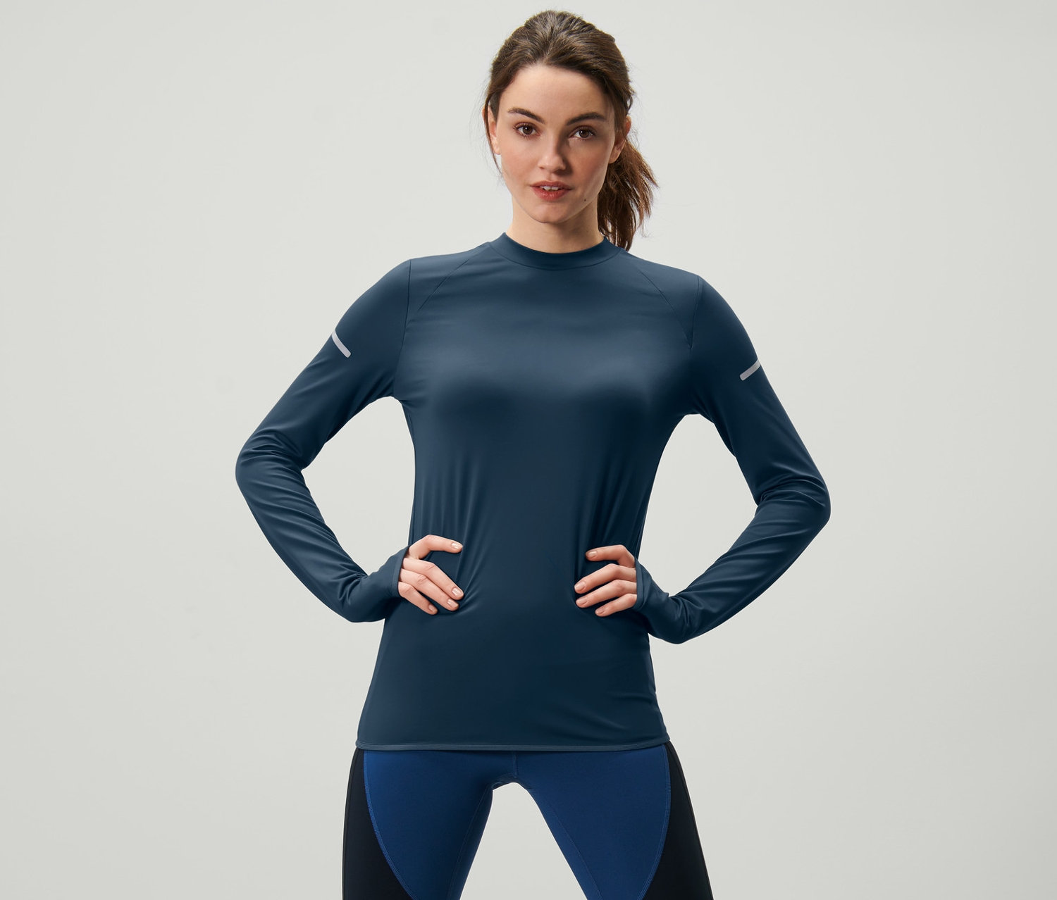Frau posiert in dunkelblauem Langarm-Funktionsshirt.
