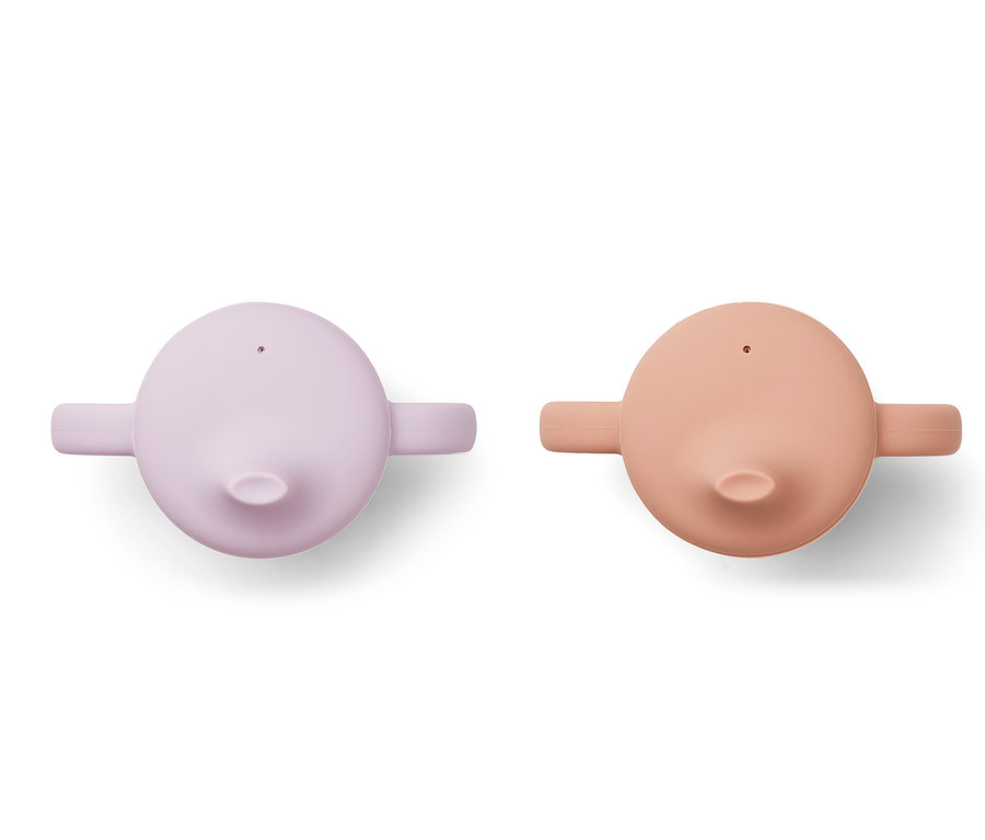 Zwei Liewood 2 Trinkbecher mit Henkeln, einer lavendelfarben, der andere lachsfarben, liegen nebeneinander.