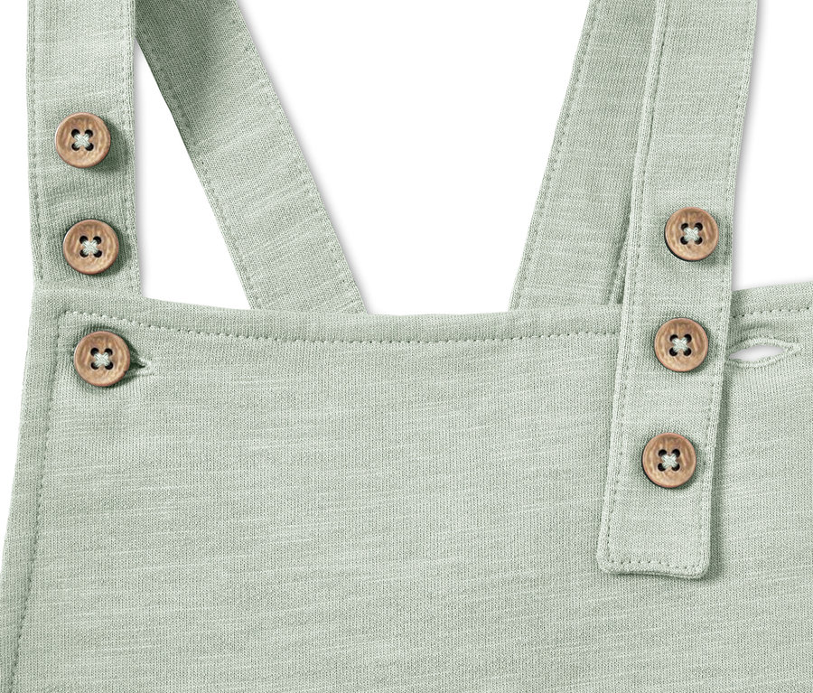Detail einer Baby-Latzhose in Mintgrün mit Holzknöpfen.