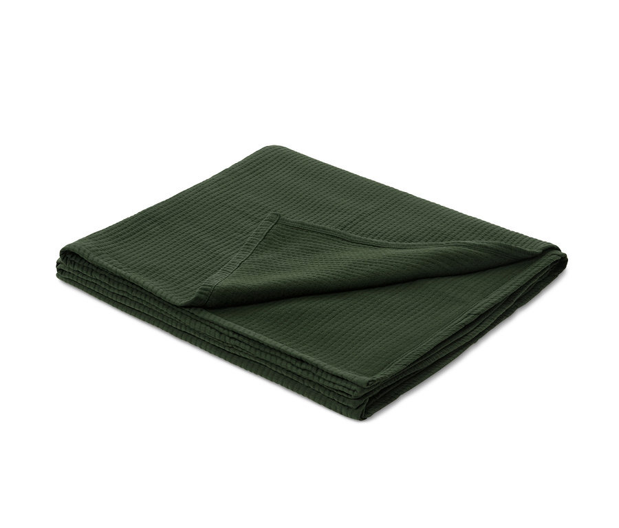 Gefaltete grüne Bettüberwurf mit Textur.