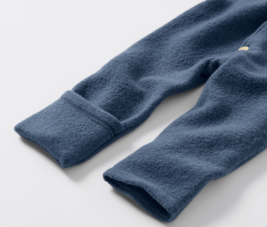 Detailansicht eines blauen Baby-Walkoveralls mit Merinowolle.