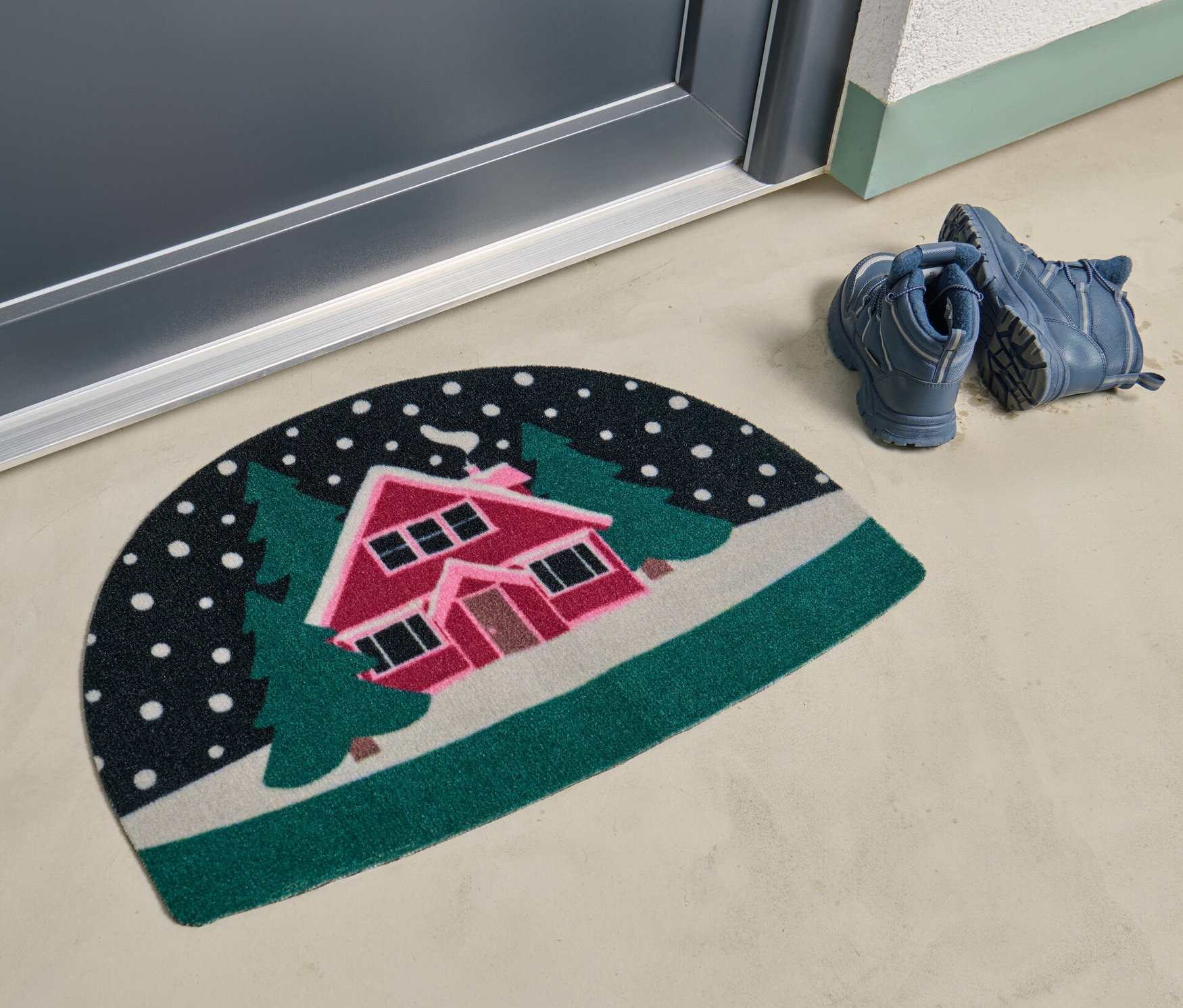 Eine Fußmatte mit einem verschneiten Landschaftsmotiv liegt vor einer Tür.