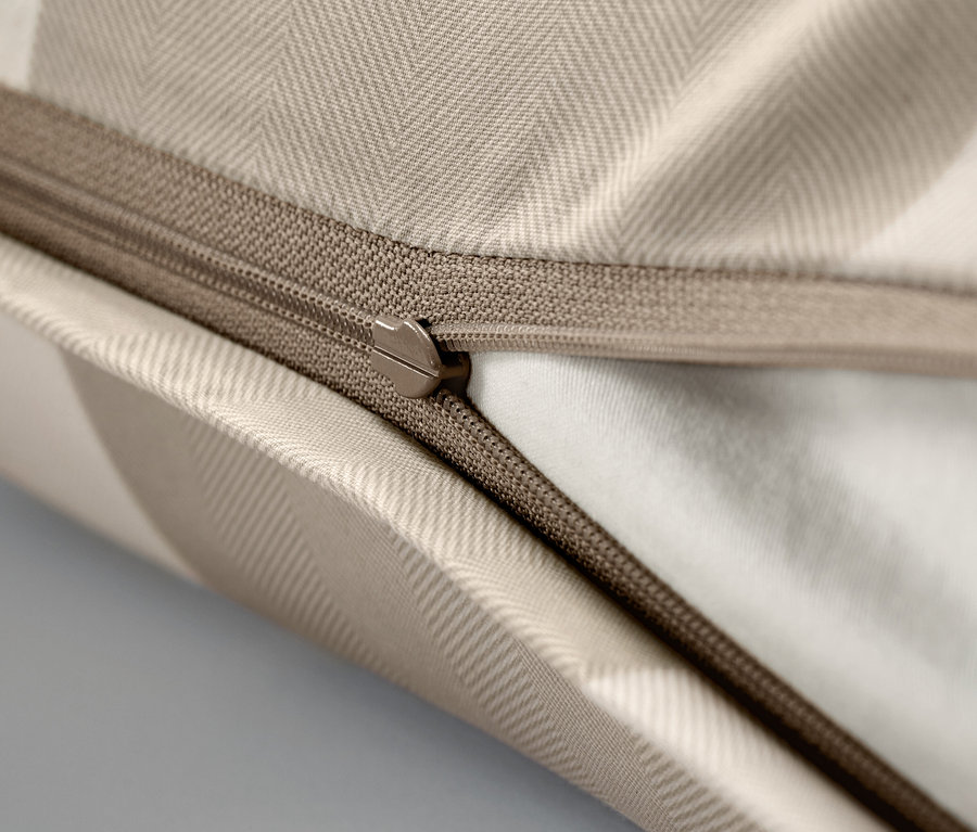Detailaufnahme eines beigen Kopfkissenbezugs mit Reißverschluss.