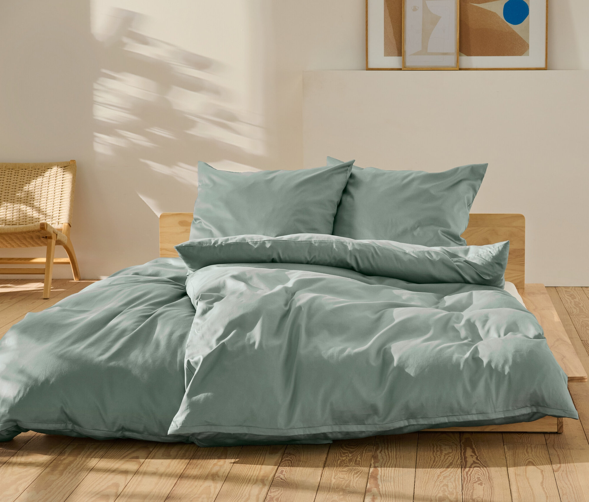 Grüne Baumwollsatin-Bettwäsche in Normal- und Übergröße auf einem Bett.