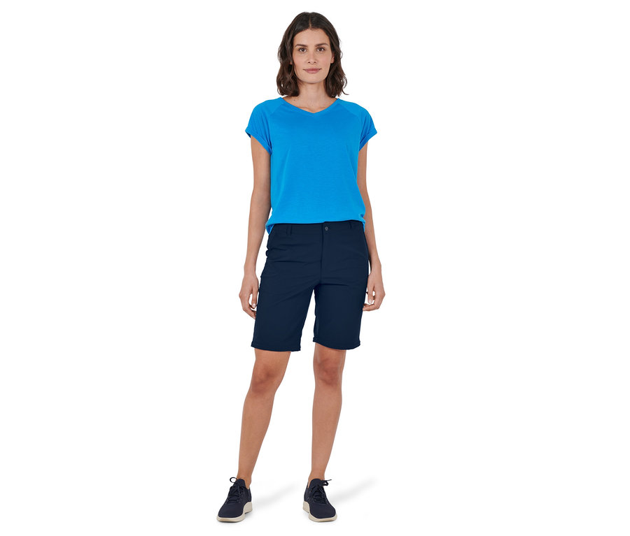 Frau steht in blauer 2-in-1-Funktionshose und blauem T-Shirt.