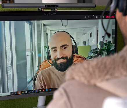 Mann schaut Videoanruf auf Monitor mit angebrachter 2-in-1-LightBar-Pro-Monitorlampe mit Full-HD-Webcam.