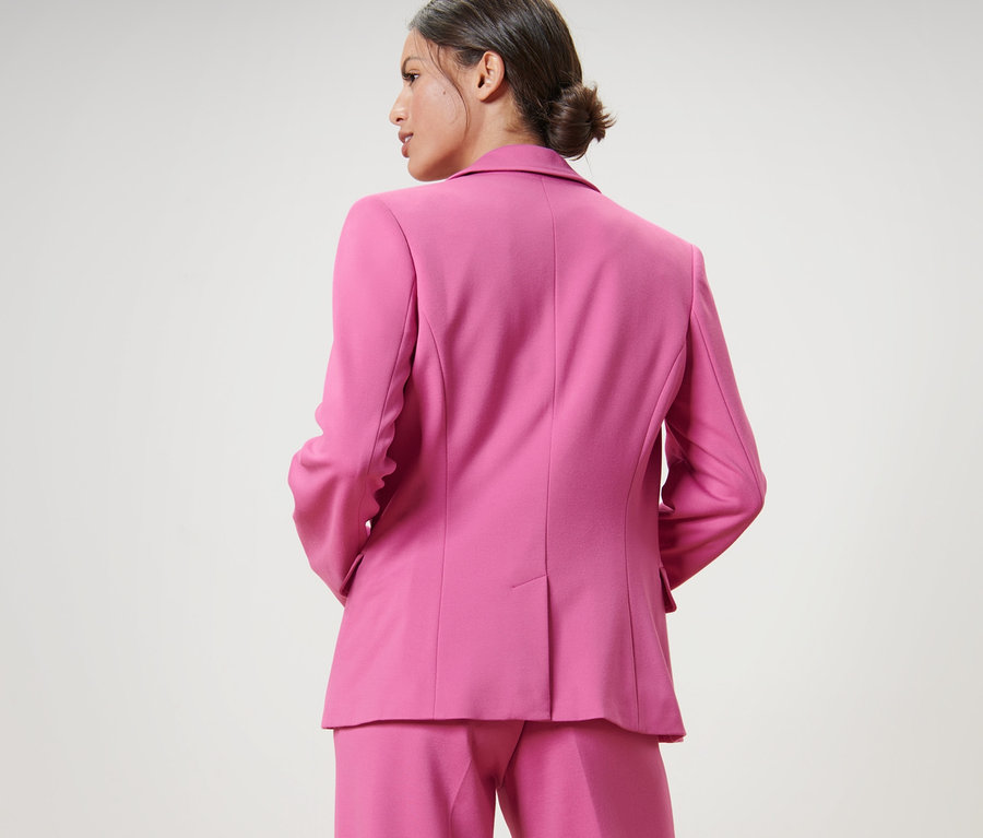 Frau trägt ein pinkes Ensemble, inklusive Jerseyblazer.