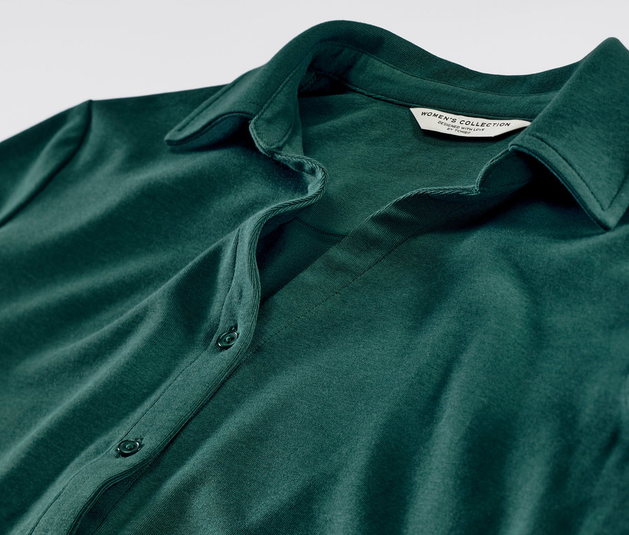 Detailansicht eines grünen Blusenshirts mit Knopfleiste.