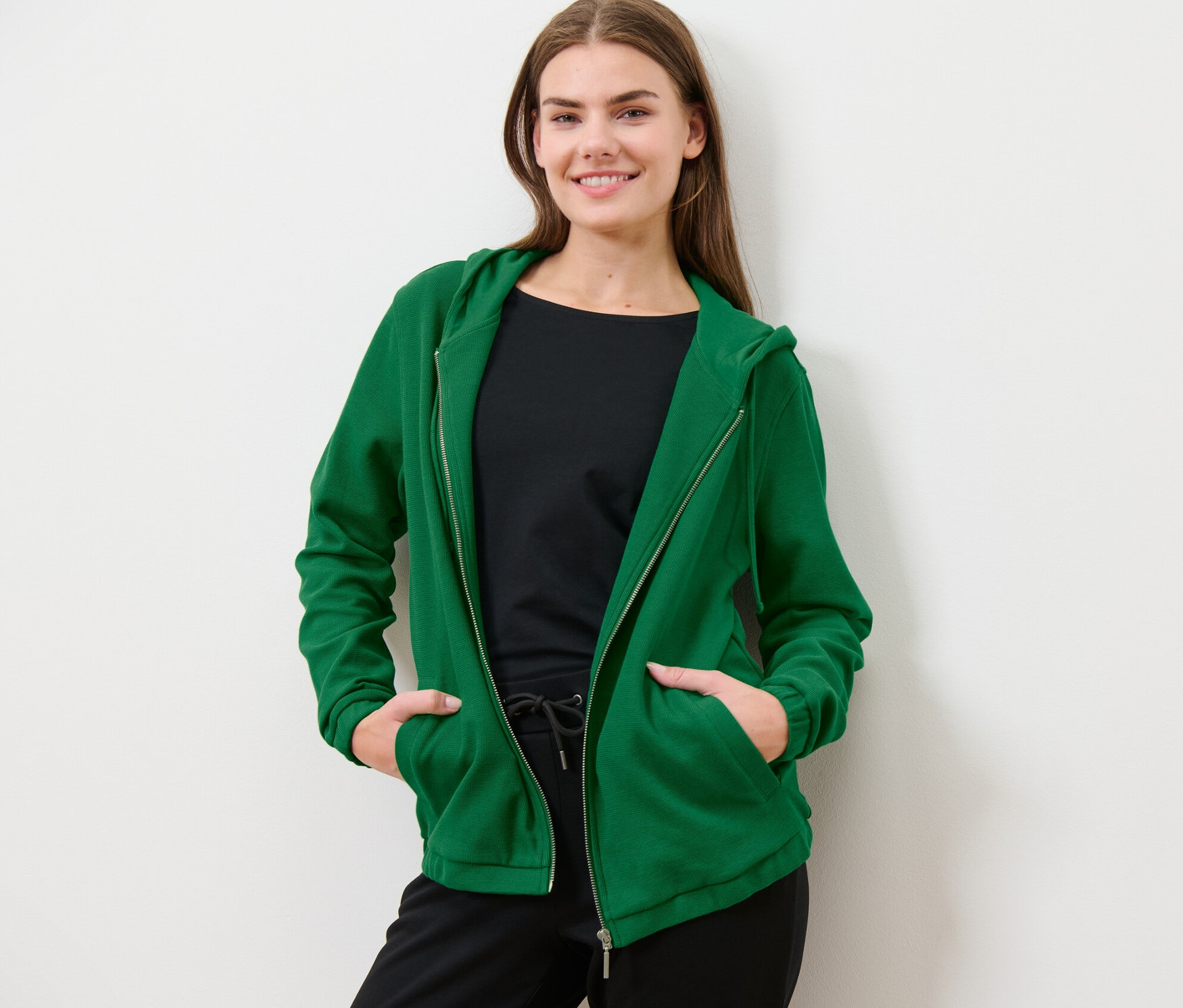 Frau posiert in grüner Sweatjacke.