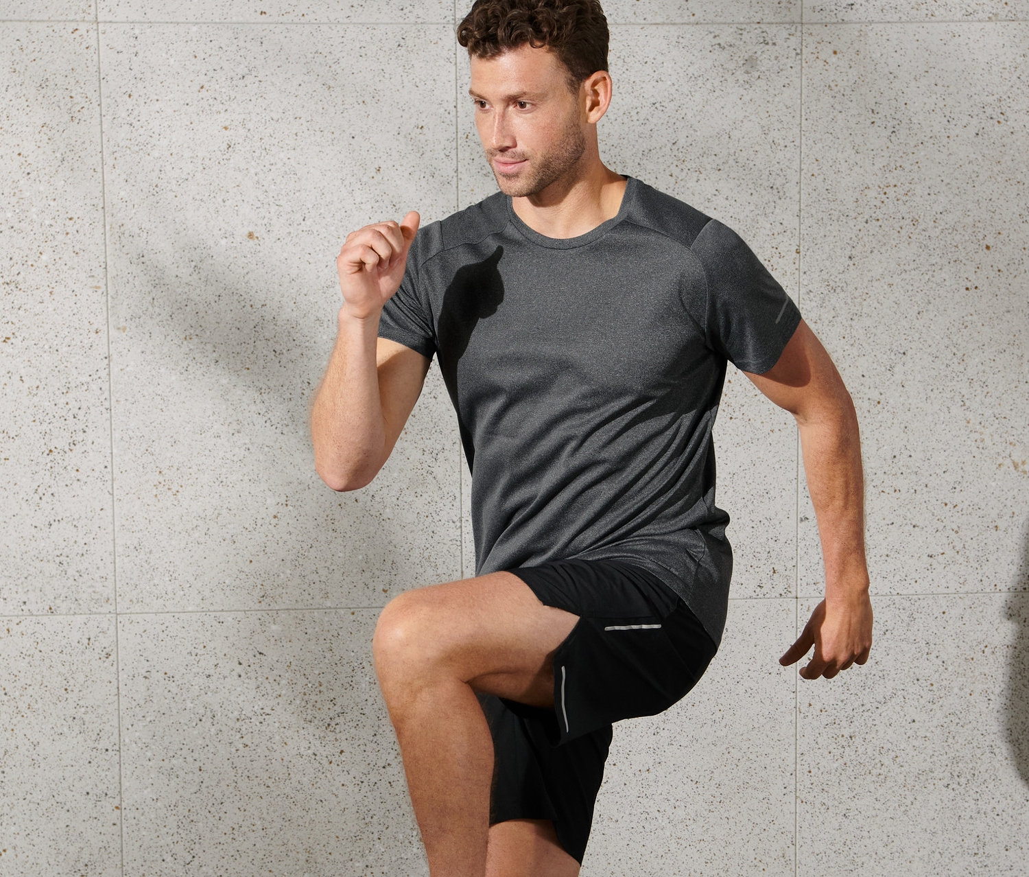 Mann trainiert in anthrazit meliertem Funktionsshirt.