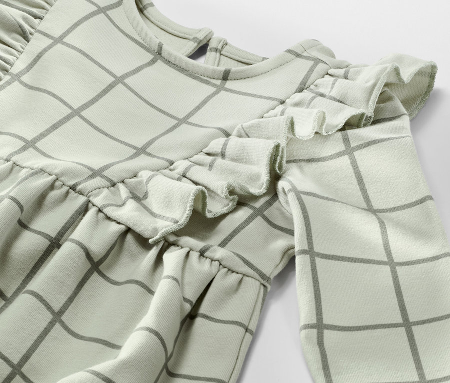 Detailansicht eines Kleinkind-Sweatkleids mit Karomuster und Rüschen.