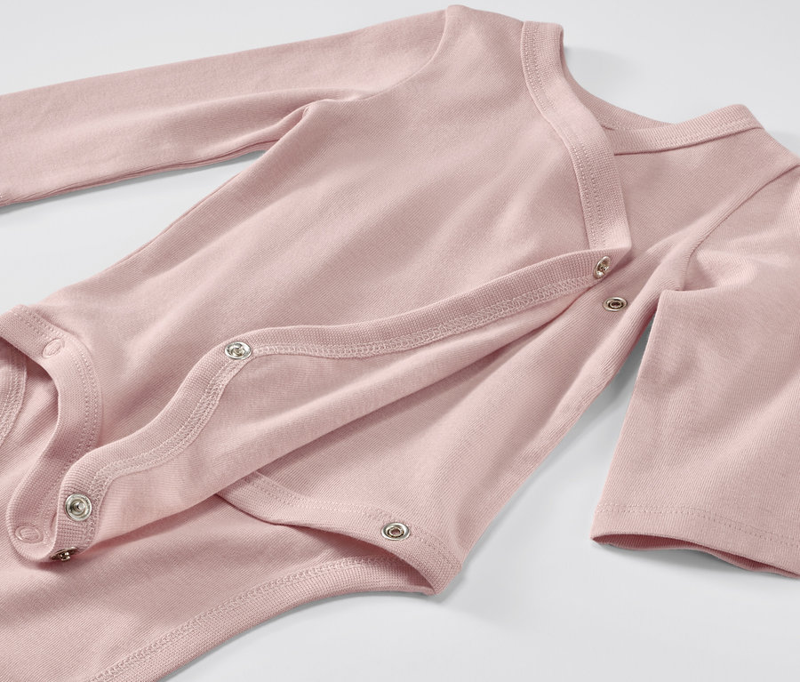 Detailansicht eines rosa Baby-Bodys mit Mitwachsfunktion und langen Ärmeln, der mit Druckknöpfen geschlossen wird.