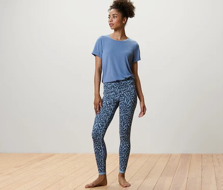 Eine Frau steht und trägt eine blau/hellblaue Wende-Sporttight und ein blaues T-Shirt.