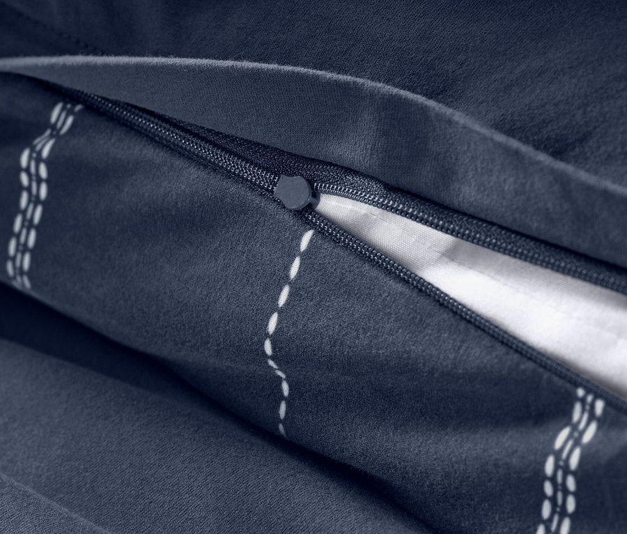 Detailansicht eines Reißverschlusses und Streifenmusters auf marineblauer Winterjersey-Bettwäsche.