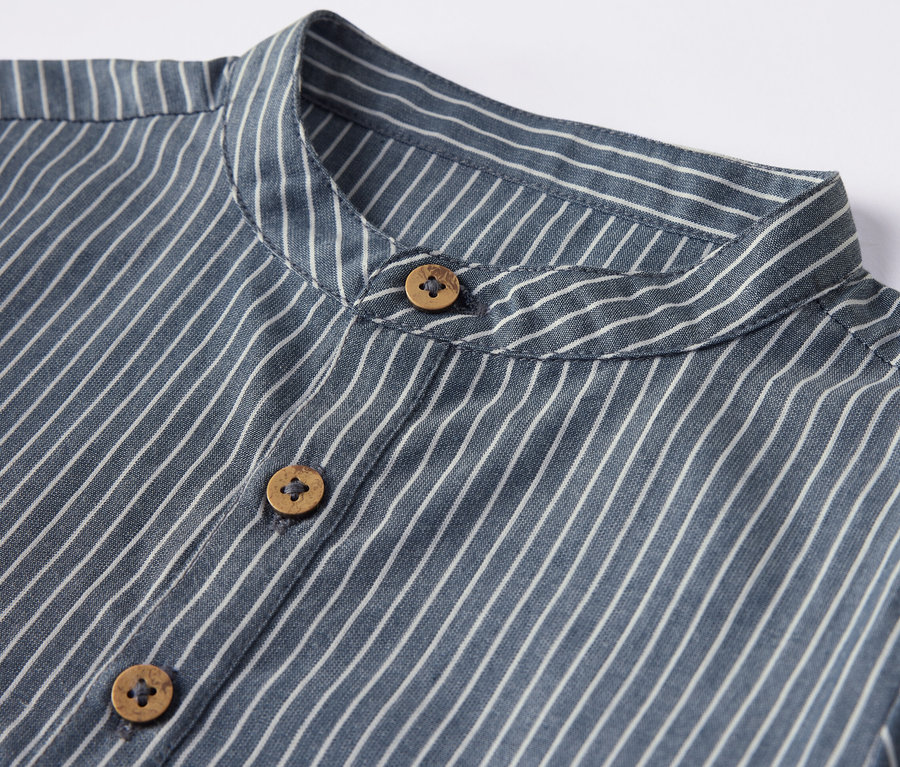 Detailansicht eines gestreiften Kinderhemdes mit Holzknöpfen.