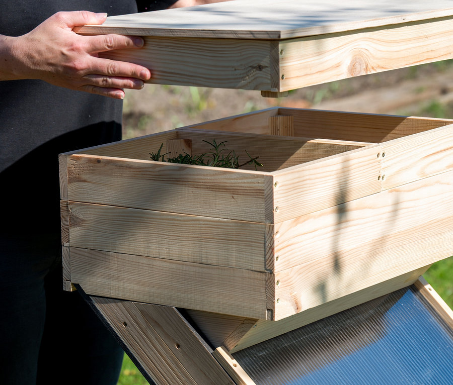 Person legt Deckel auf Solar-Dörrschrank aus Holz.