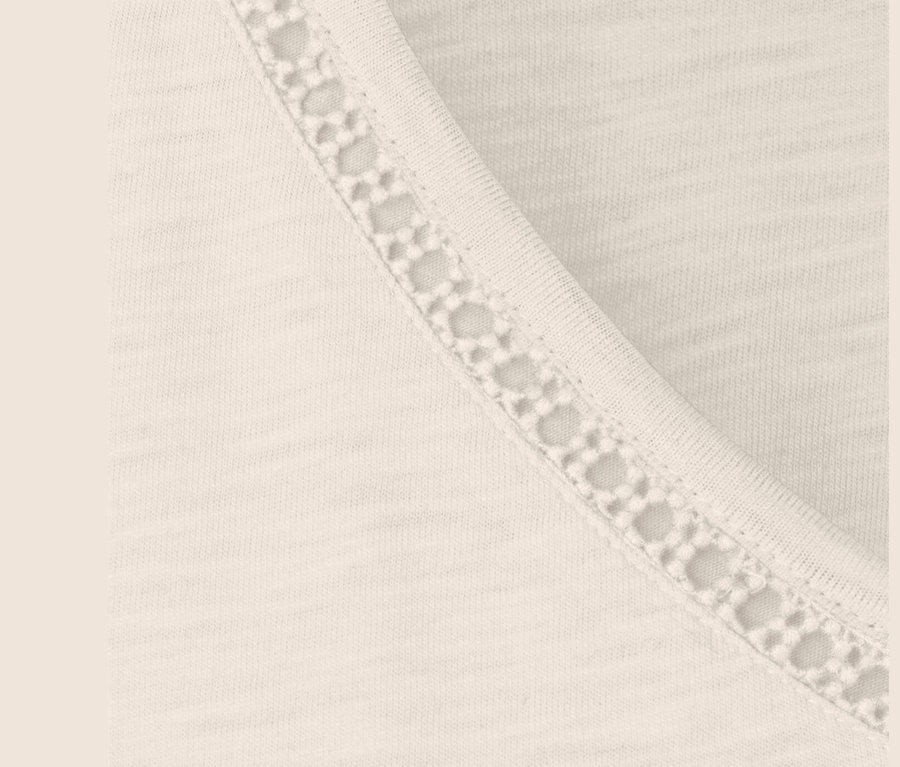 Detailansicht eines cremeweißen Shirts aus Modalmix mit Spitzenbesatz.