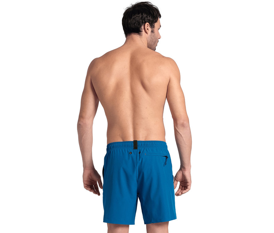 Mann von hinten trägt blaue Badeshorts.