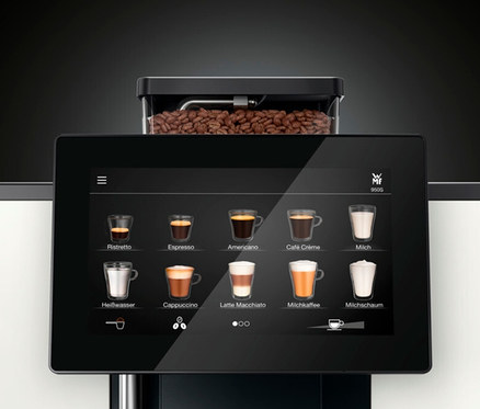 Detailaufnahme eines WMF 950 S Kaffeevollautomaten mit Display, das verschiedene Kaffeevarianten zeigt.