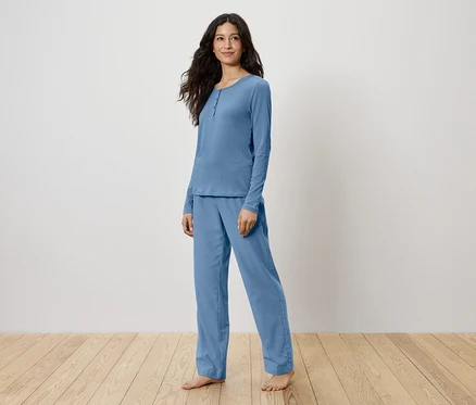 Eine Frau steht und trägt einen hellblauen Pyjama.