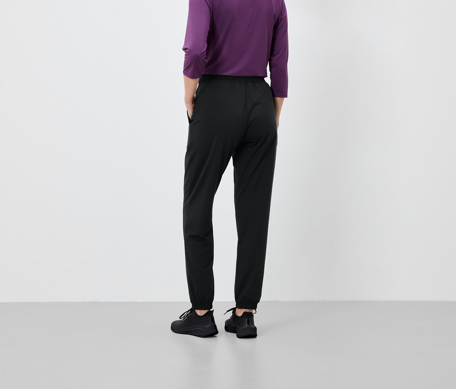 Person von hinten, trägt schwarze Hose und lila Shirt.