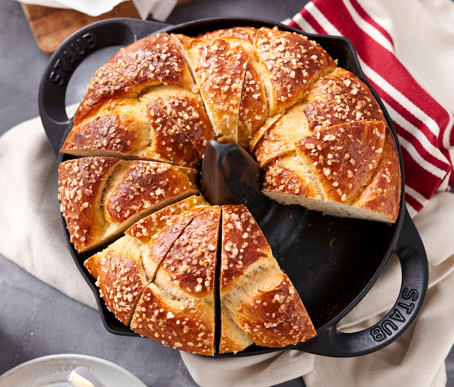 Ein in Stücke geschnittener, bestreuter Kuchen in einem schwarzen STAUB Hähnchen-Bräter.