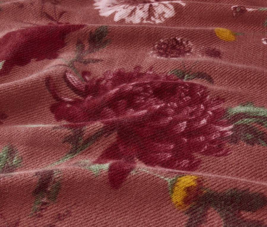Nahaufnahme eines Stoffes mit Blumenmuster in Rosa- und Grüntönen.