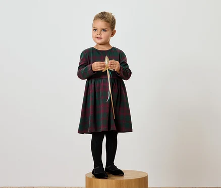 Mädchen im karierten Kleid hält goldenen Stern.